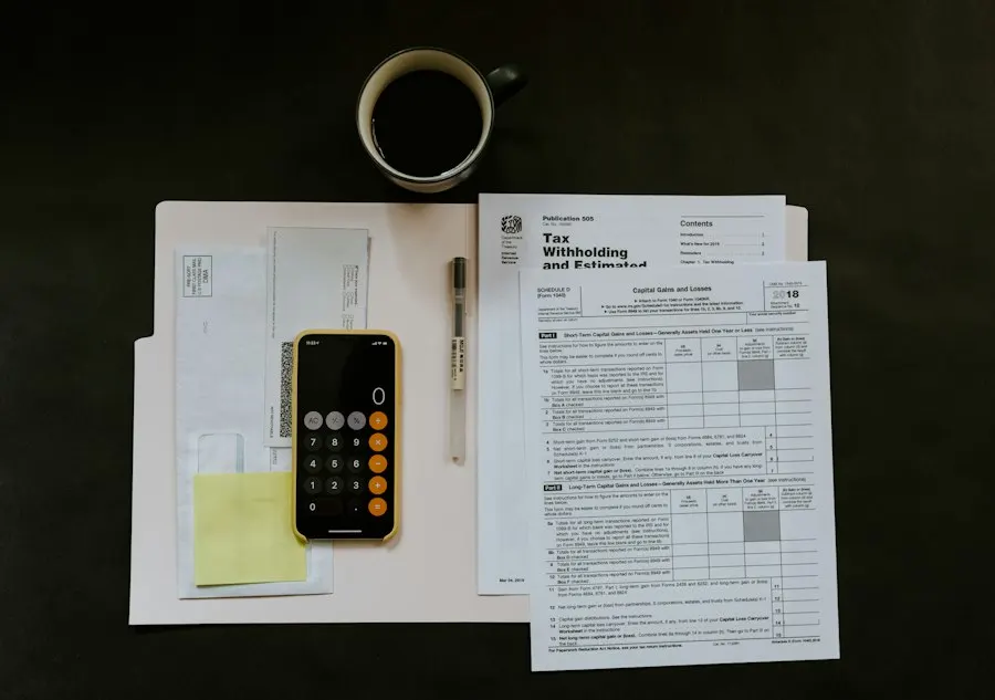 Paper forms in a folder next to a phone calculator, a pen and a cup of coffee