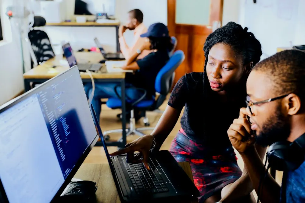Two people looking at a laptop together in a shared office
